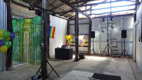DJ and lighting rig set up inside the shed with speakers and balloons, ready for a function.