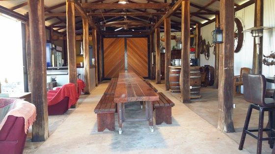 The long jarrah table set up inside the shed, viewed toward the closed timber doors.