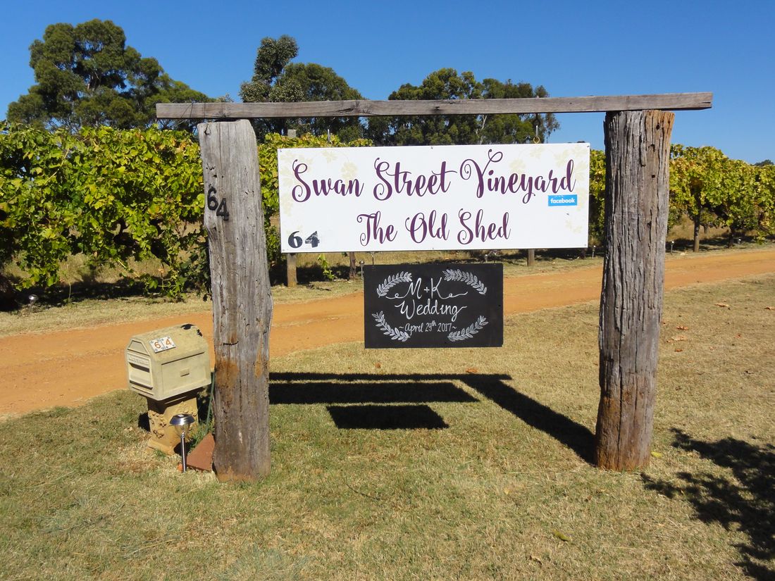 Freestanding LOVE letters, hay-bale seating and a rustic wagon wheel set up outdoors in the vineyard for a wedding.