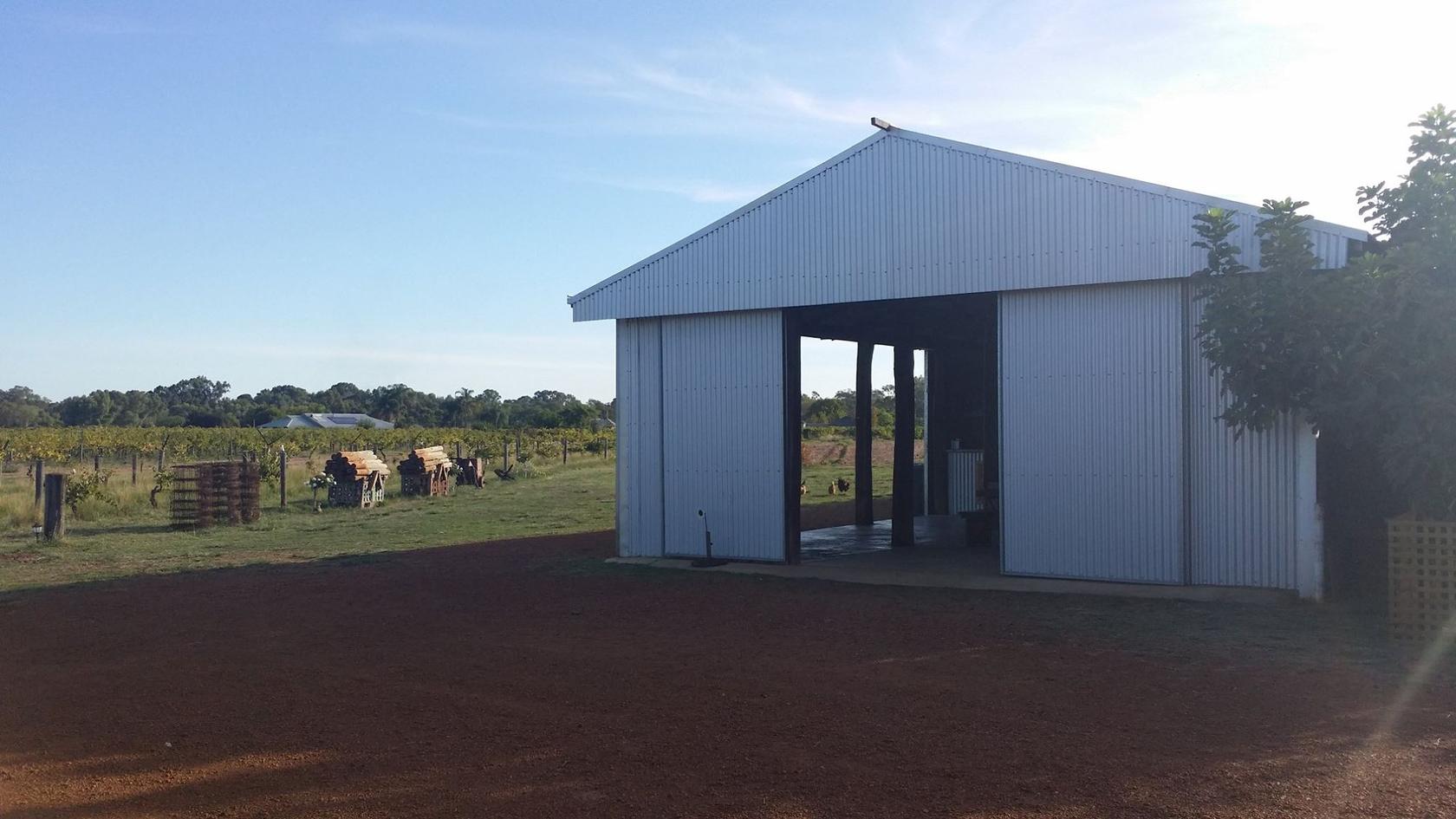 The Old Shed at Swan Street Vineyard lit up in golden late-afternoon light, its corrugated iron walls and gabled roof set against the Swan Valley sky.